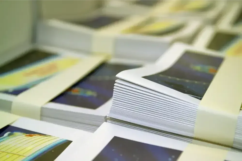 Stacks of glossy printed booklets with white bands on a table