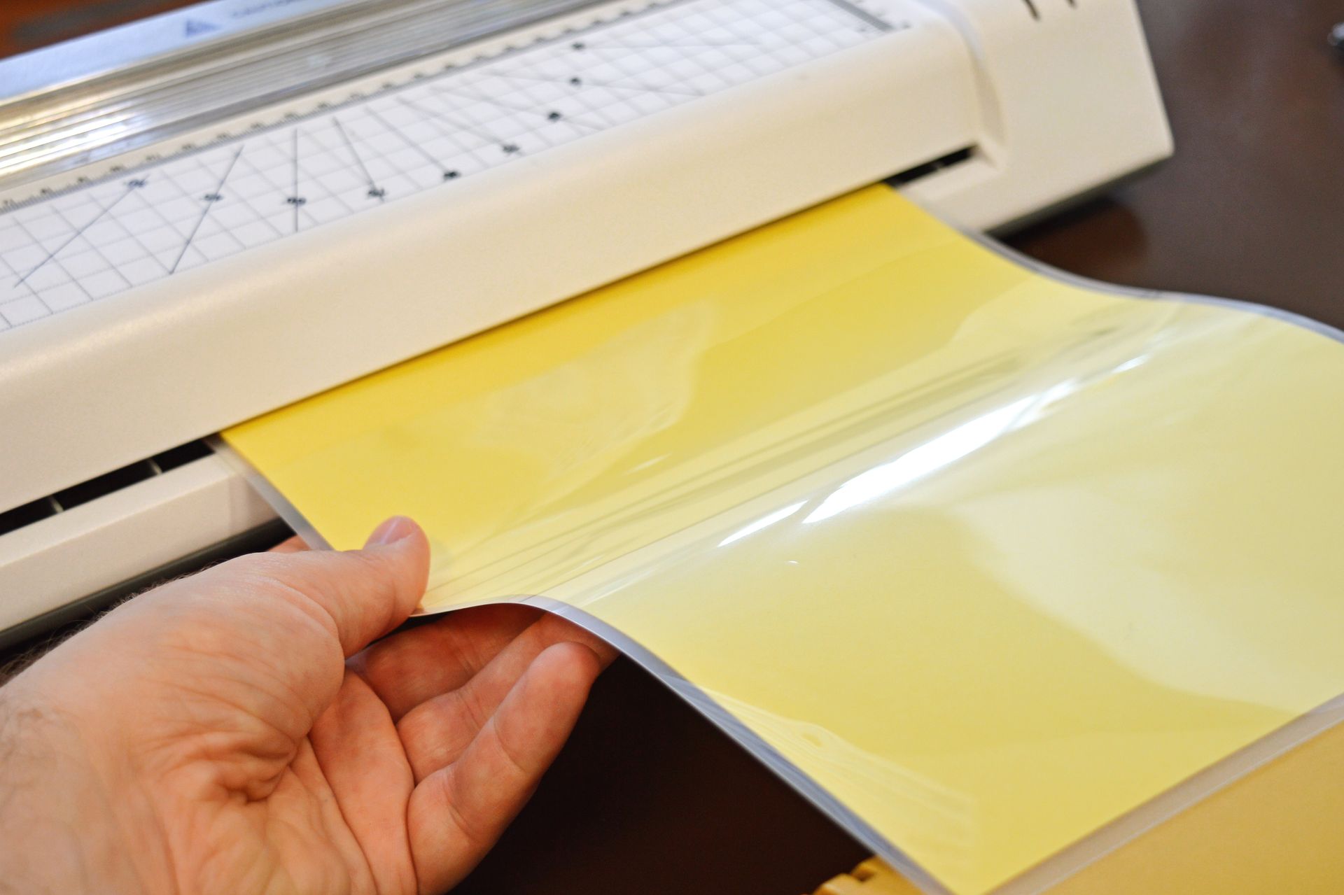 Hand feeding yellow adhesive vinyl into a cutting machine