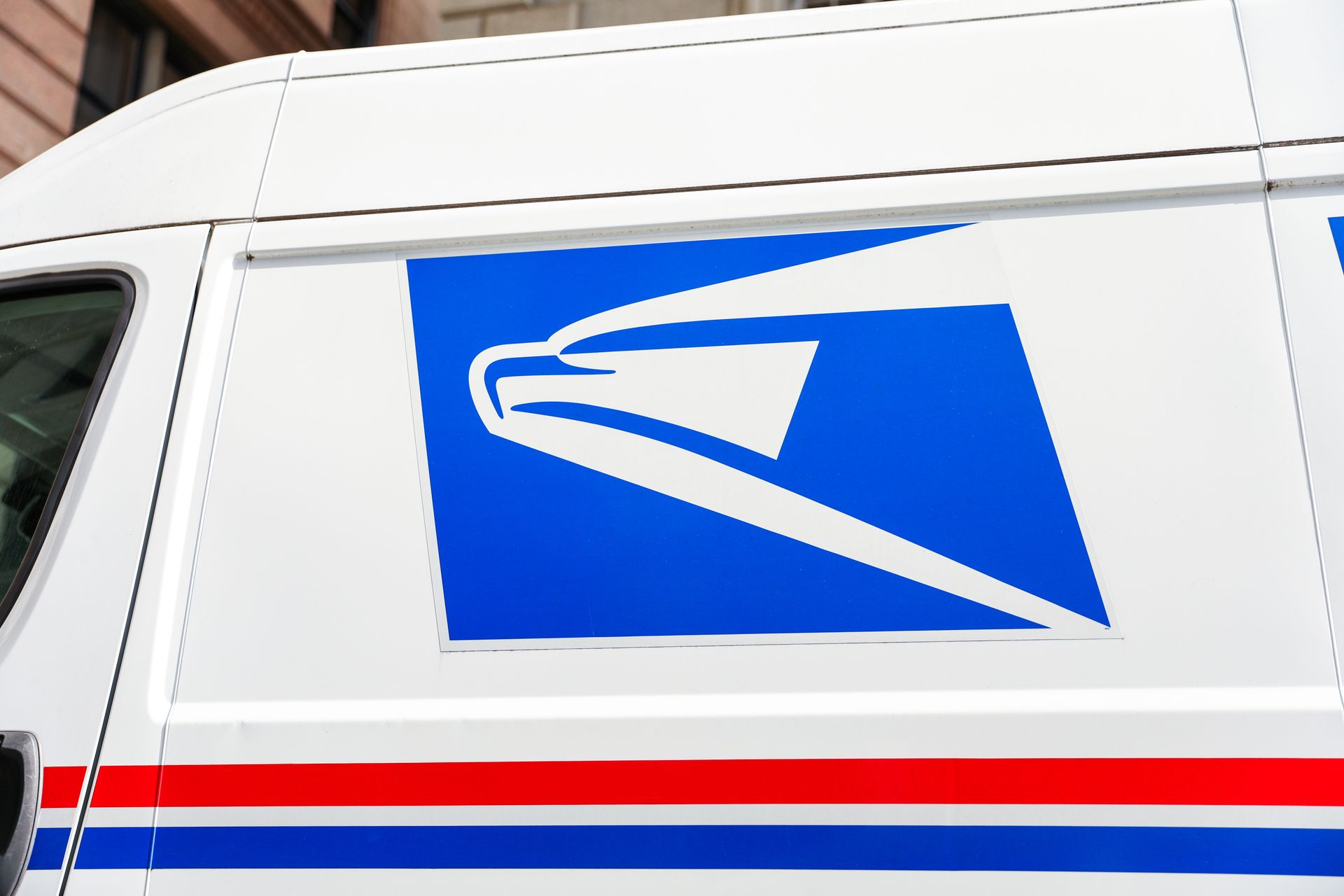 USPS mail truck side with blue eagle logo and red-and-blue stripes