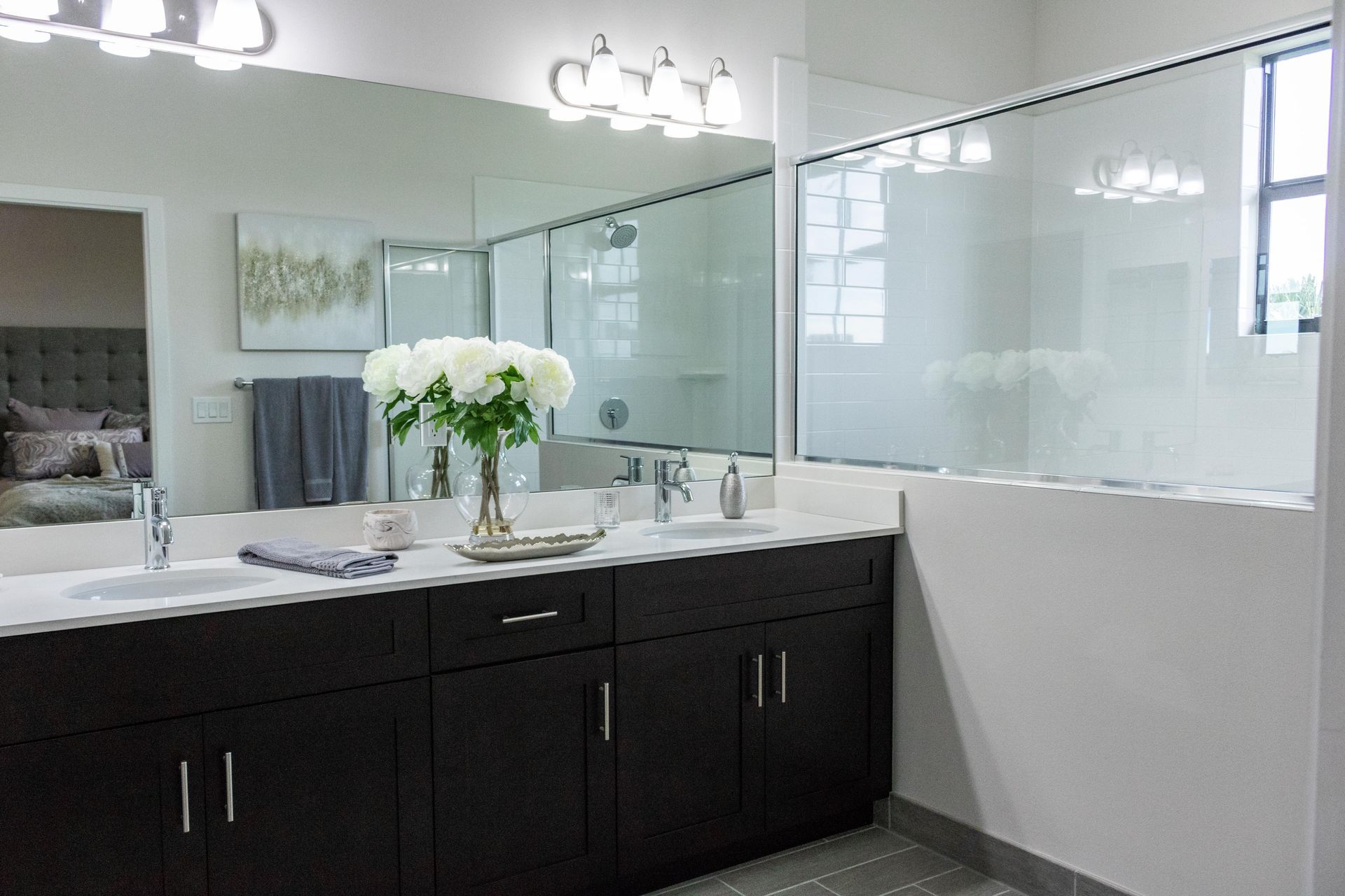 A bathroom with two sinks , a large mirror and a walk in shower.
