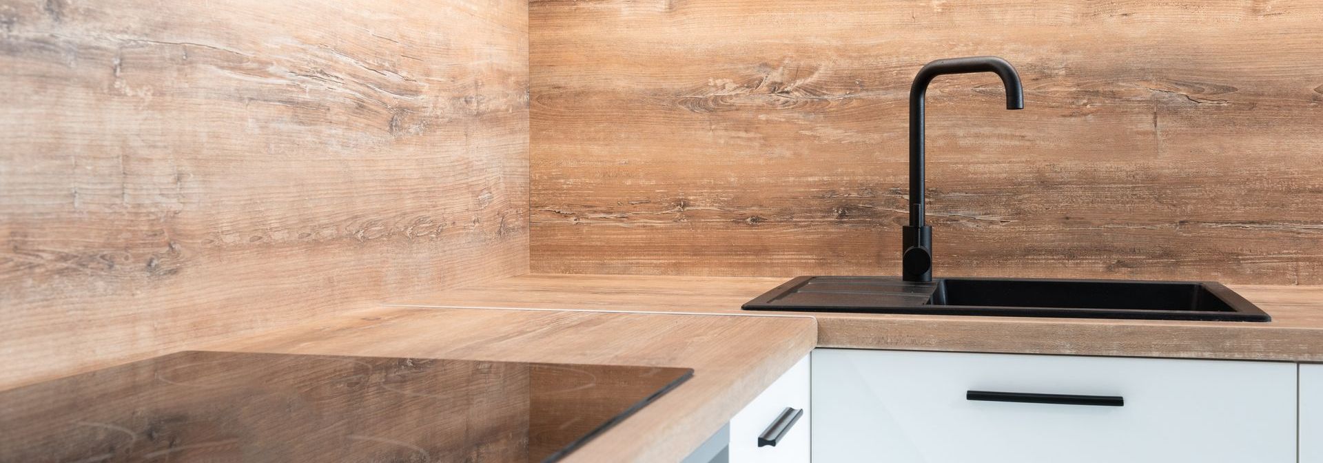 A kitchen with a black sink and a wooden wall.