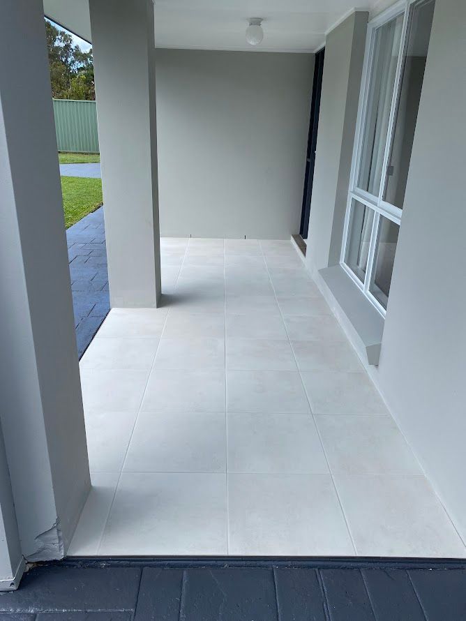 A white tiled porch with a window in a house.