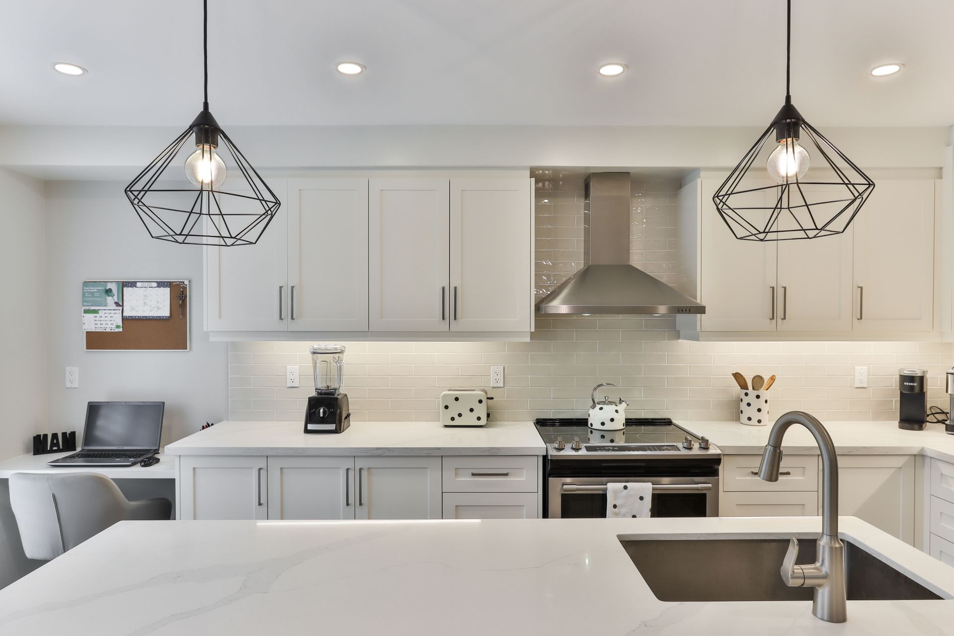 A kitchen with white cabinets , stainless steel appliances , a sink and a stove.