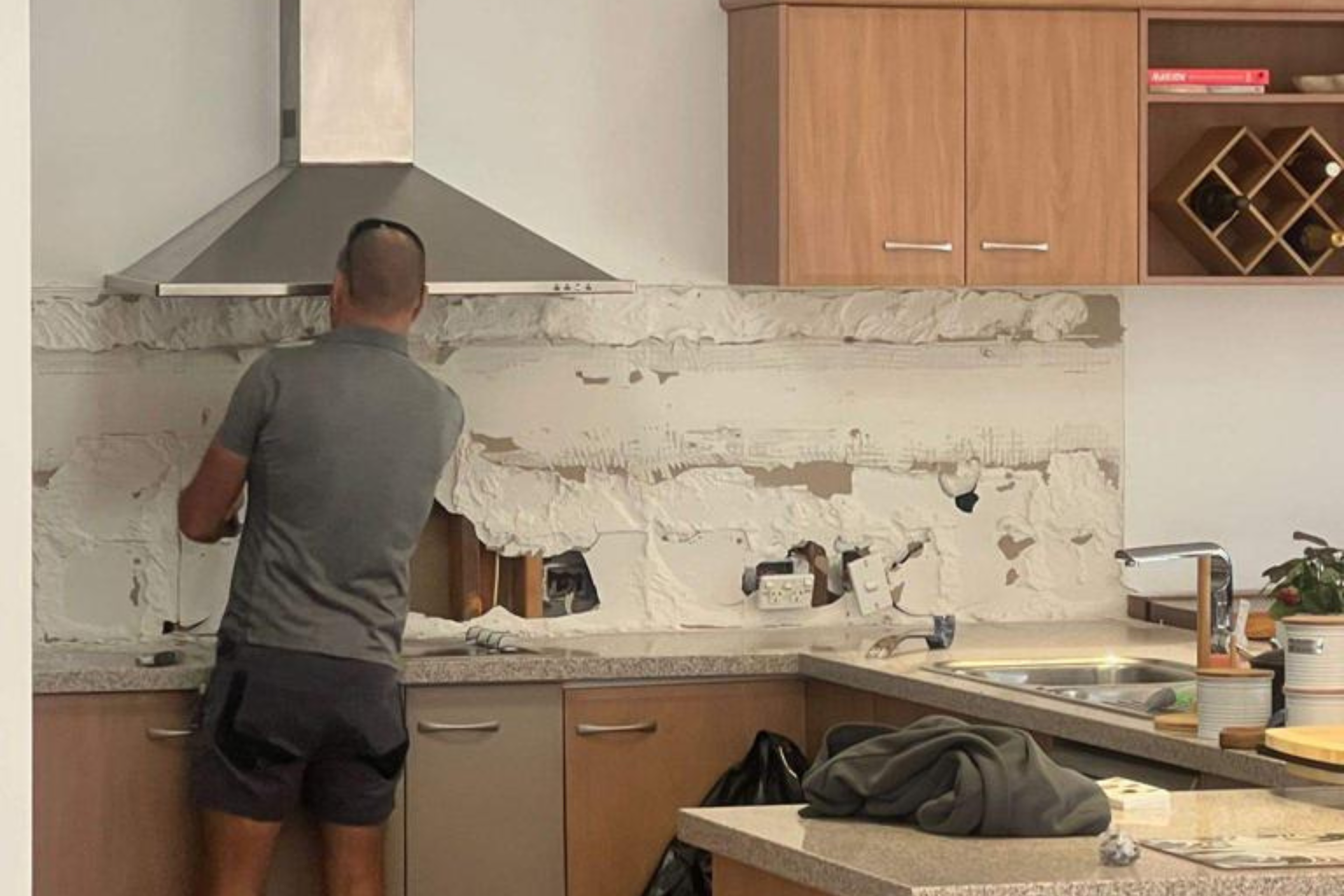 A man is working on a wall in a kitchen.