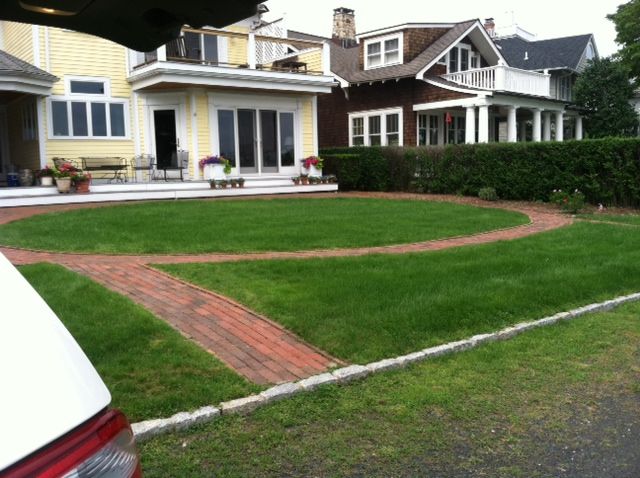 Large house with a red-brick circular driveway and a manicured green lawn