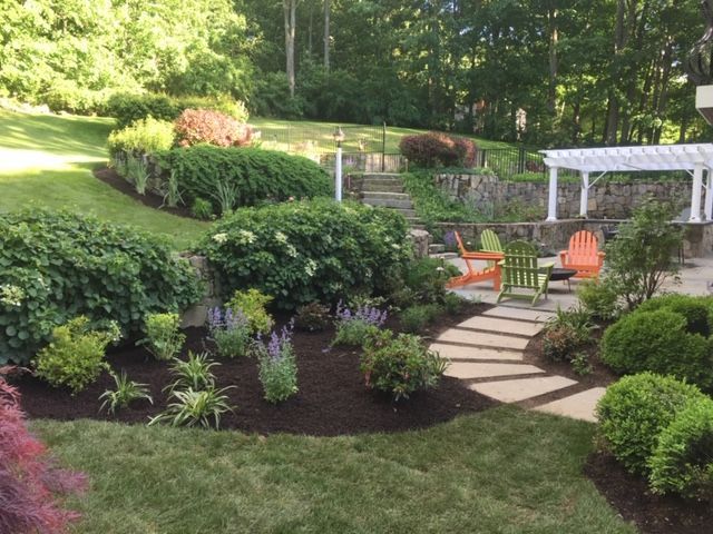 Landscaped garden with stone path, orange chairs, and a white gazebo on a terraced hillside