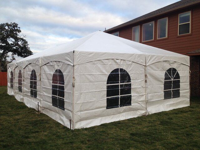 A Large White Tent is Sitting in the Grass in Front of a House