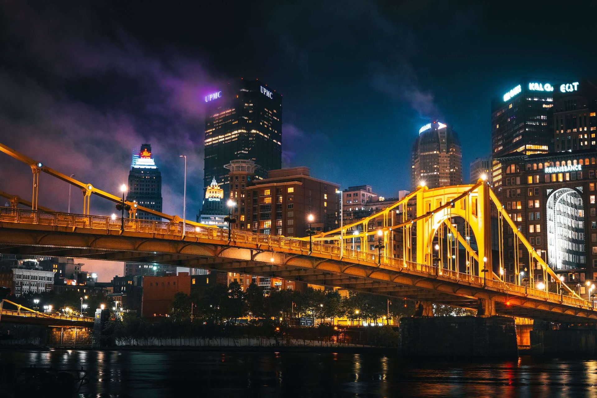 A bridge over a river in a city at night.