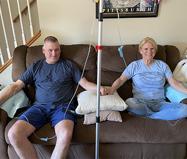 A man and a woman are sitting on a couch holding hands
