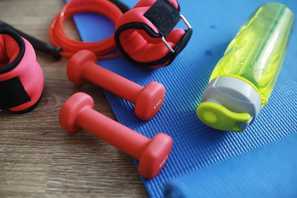 A pair of red dumbbells sitting on top of a blue yoga mat.