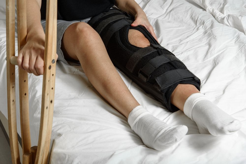 Person resting with a knee brace after surgery