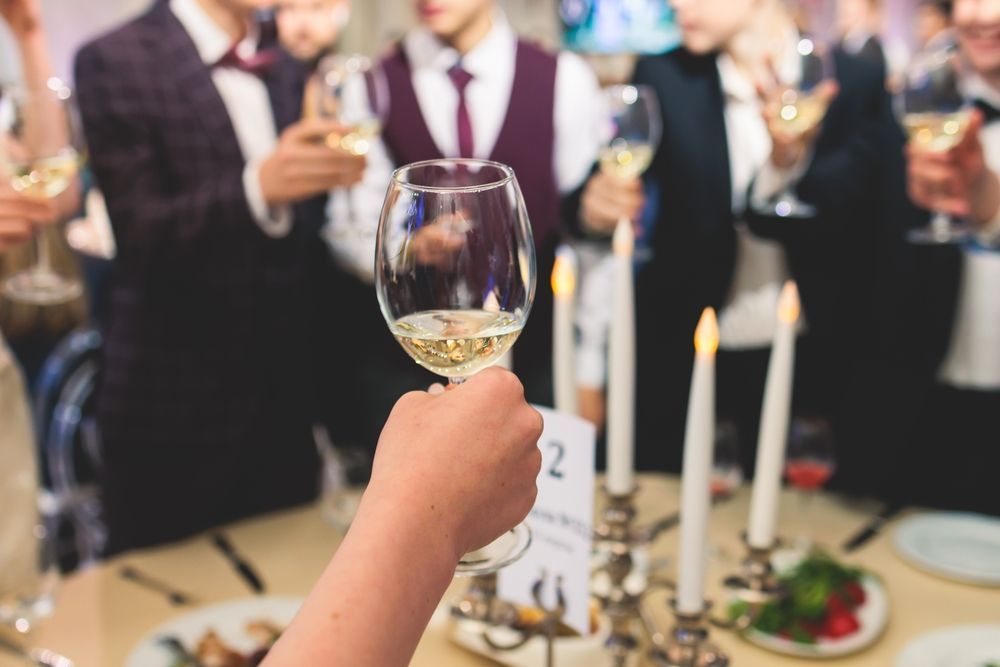 A person is holding a glass of wine in front of a group of people.
