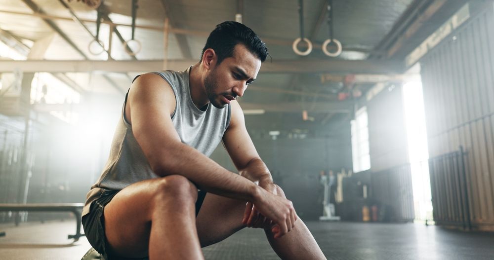 A man is sitting on the floor in a gym.