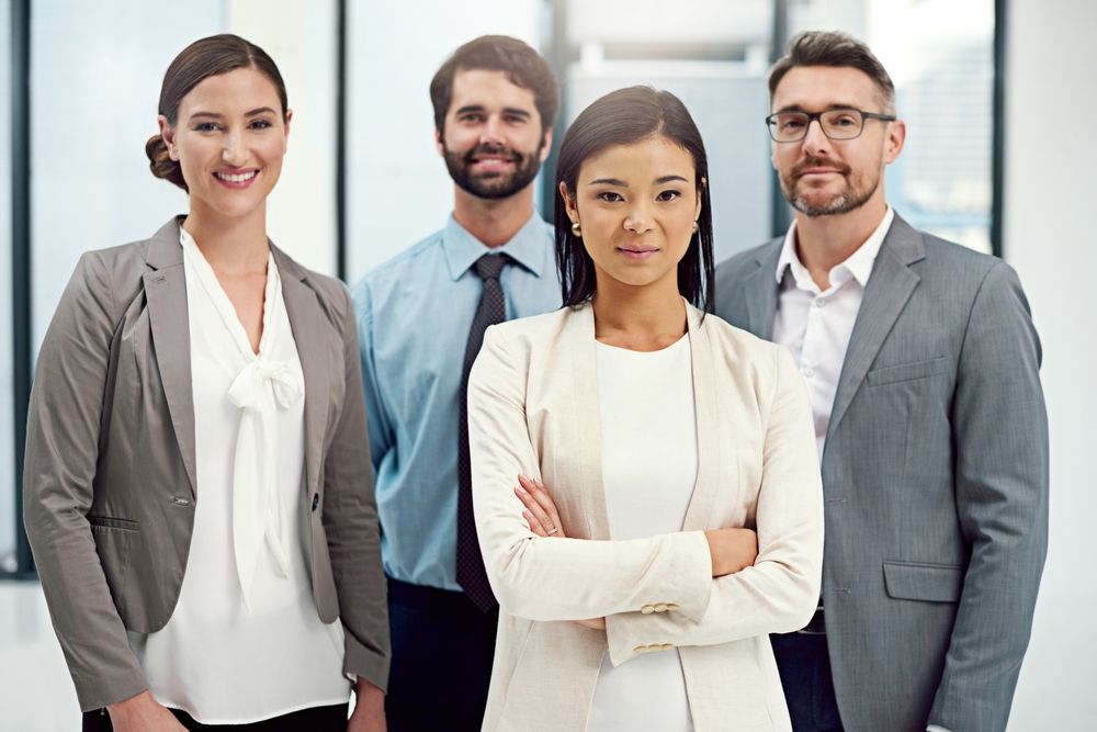A group of business people are posing for a picture together in an office.