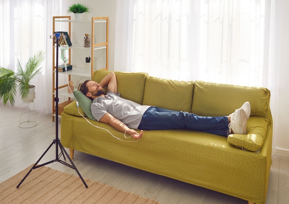 A man is laying on a couch listening to music.