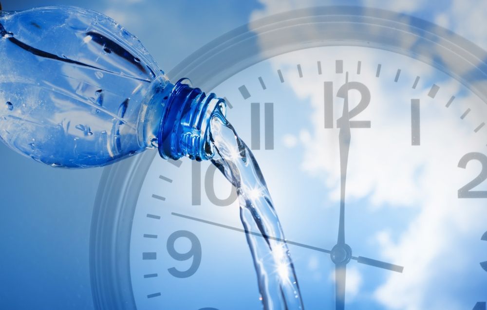 A bottle of water is being poured into a clock