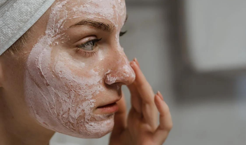 Yüzüne pembe bir maske sürülmüş bir kişi, burnuna hafifçe dokunuyor.