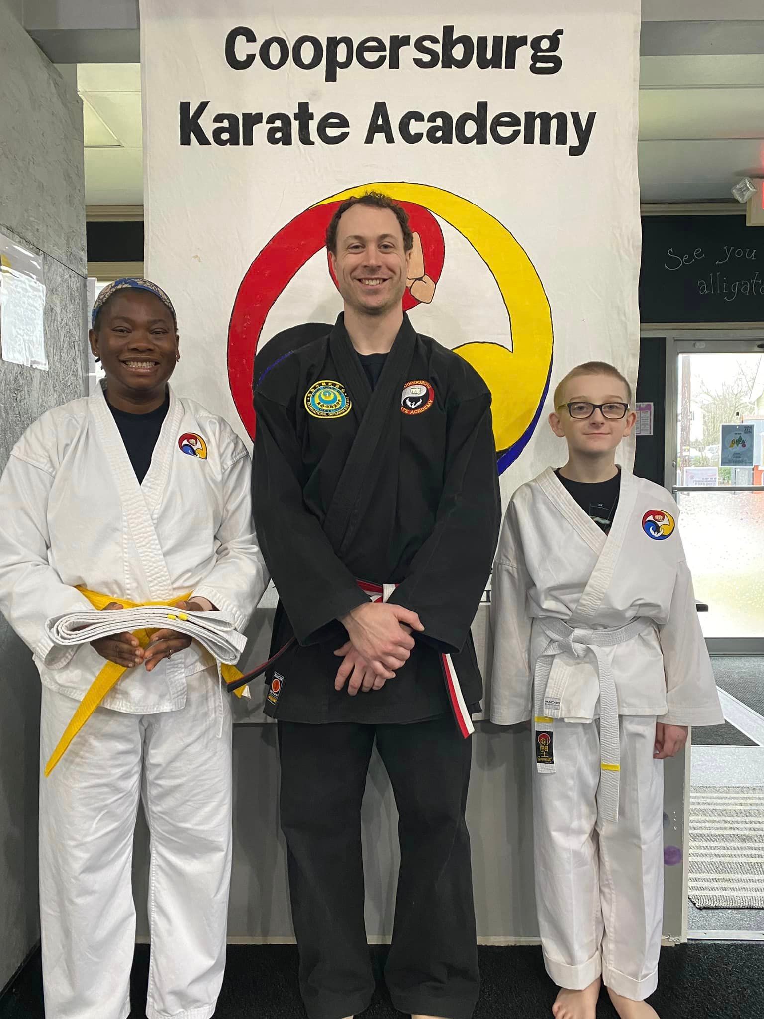 A boy in a karate uniform is standing next to a wooden box