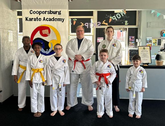 Students standing in front of a sign that says Coopersburg Karate Academy