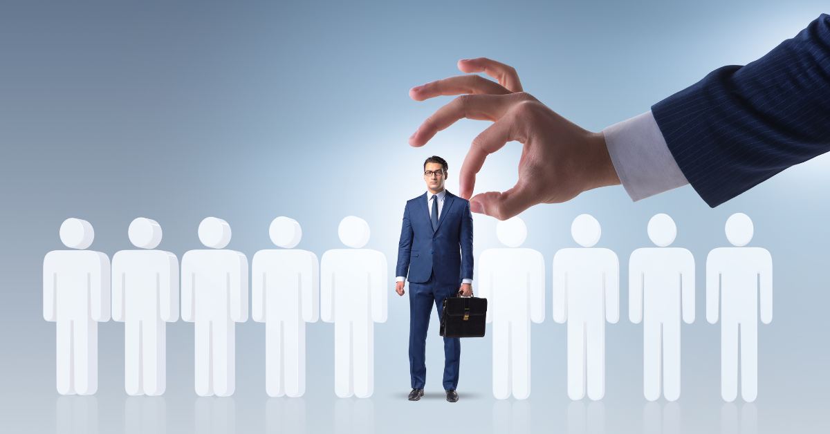 man getting picking out of a line of other people by a large hand.