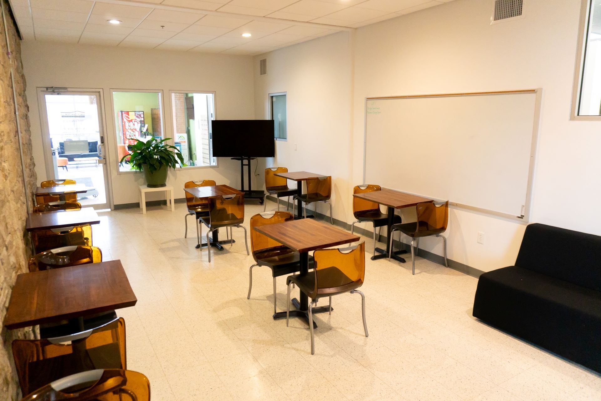 large conference room with white board tables and chairs and a tv screen