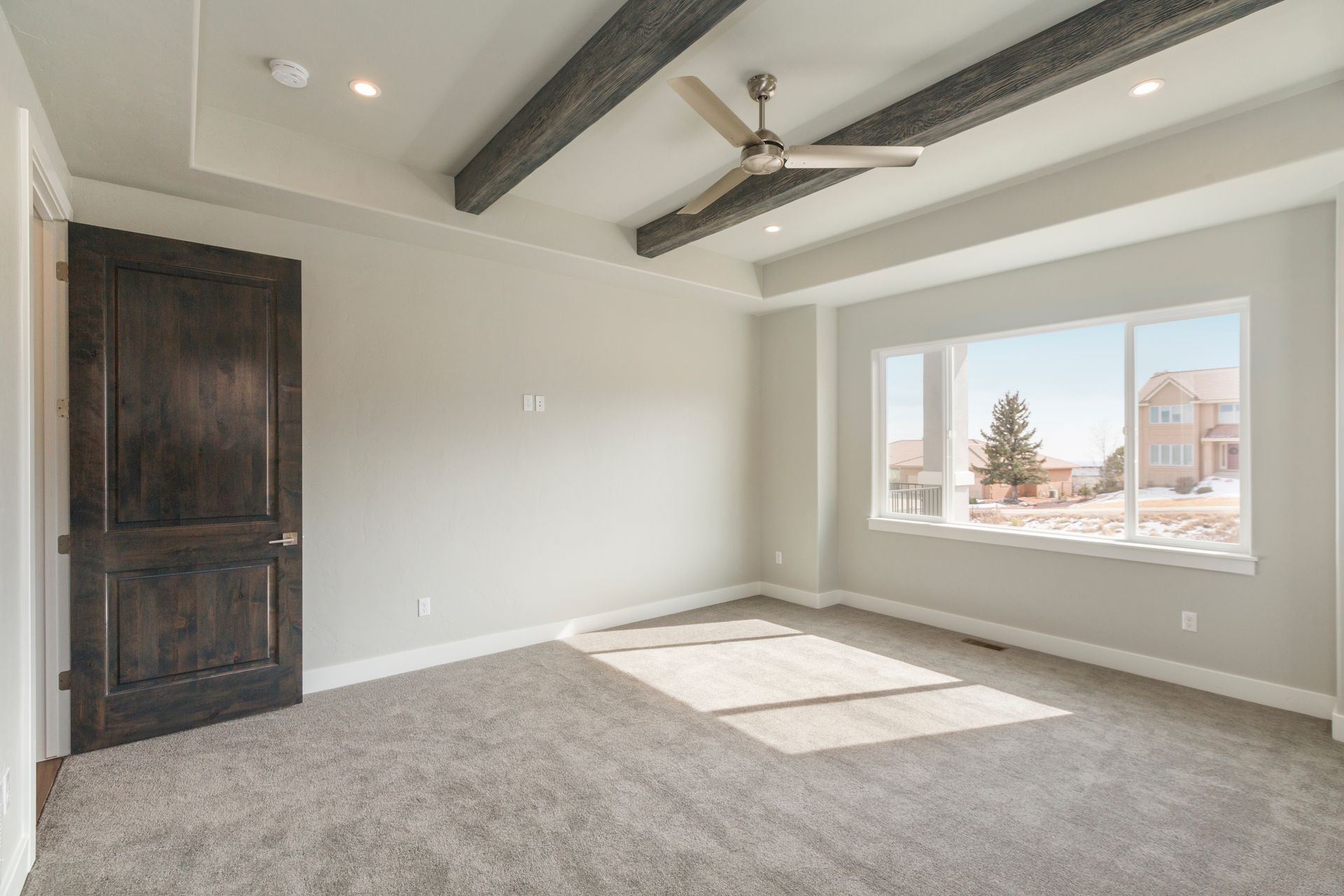 An empty bedroom with a ceiling fan and a large window.