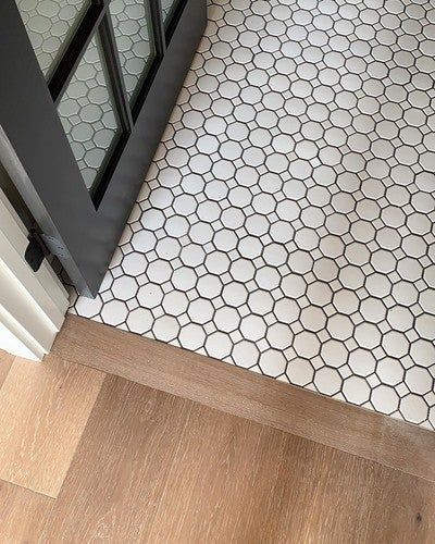 a close up of a white tile floor with a wooden floor .