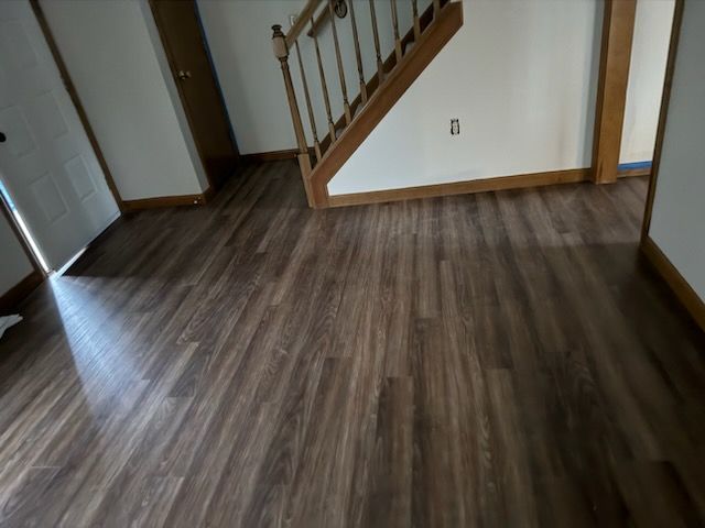 A hallway with stairs and a wooden floor