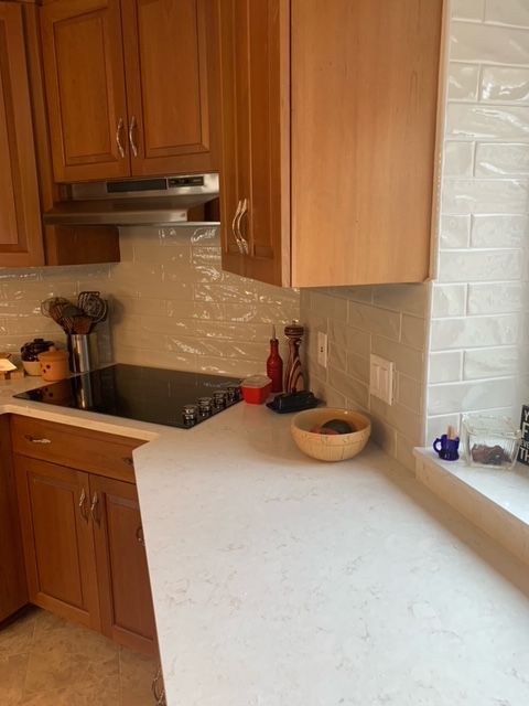 a kitchen with wooden cabinets and a white counter top. backsplash installed by Holyoke Millwork.