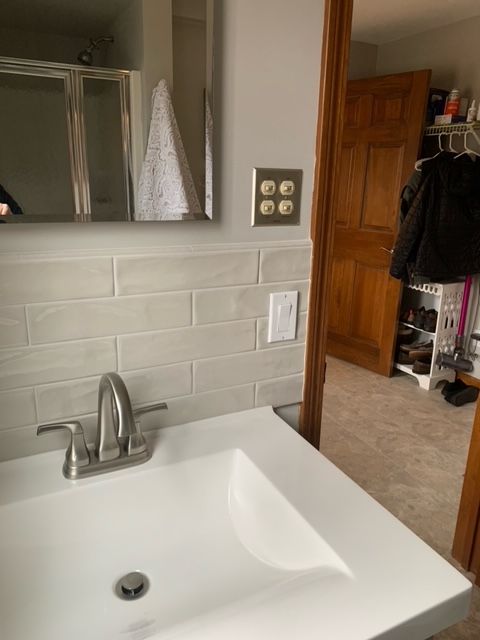 a bathroom sink with a faucet and a mirror. Tile installed by Holyoke Millwork in Holyoke, MA.