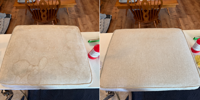 Person vacuuming a gray ottoman with a handheld upholstery attachment
