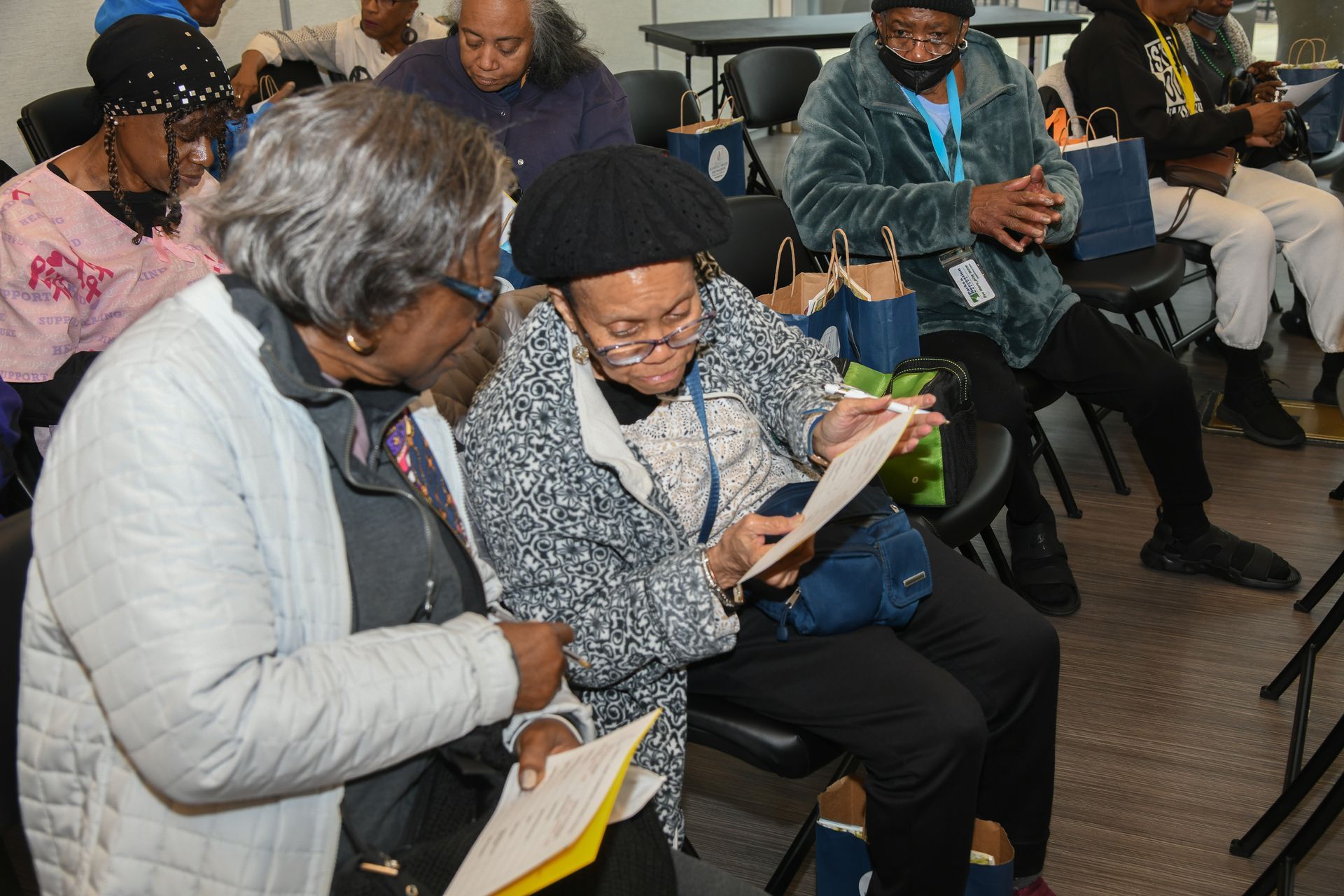 a group of people are sitting in chairs looking at papers .