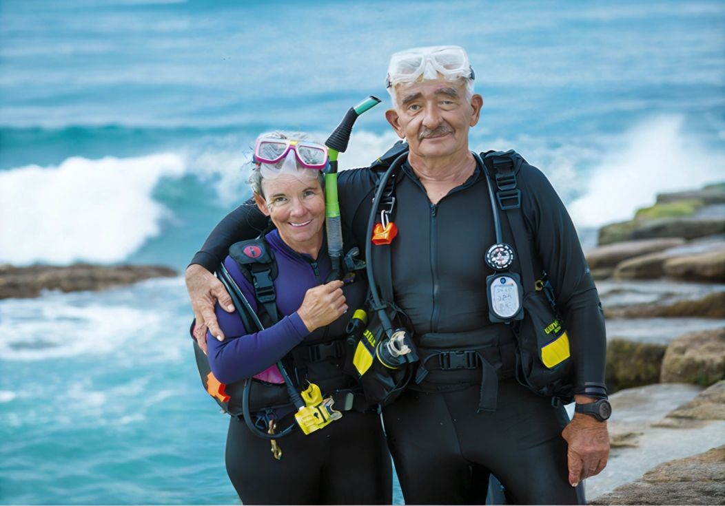 A man and a woman in wet suits are posing for a picture.