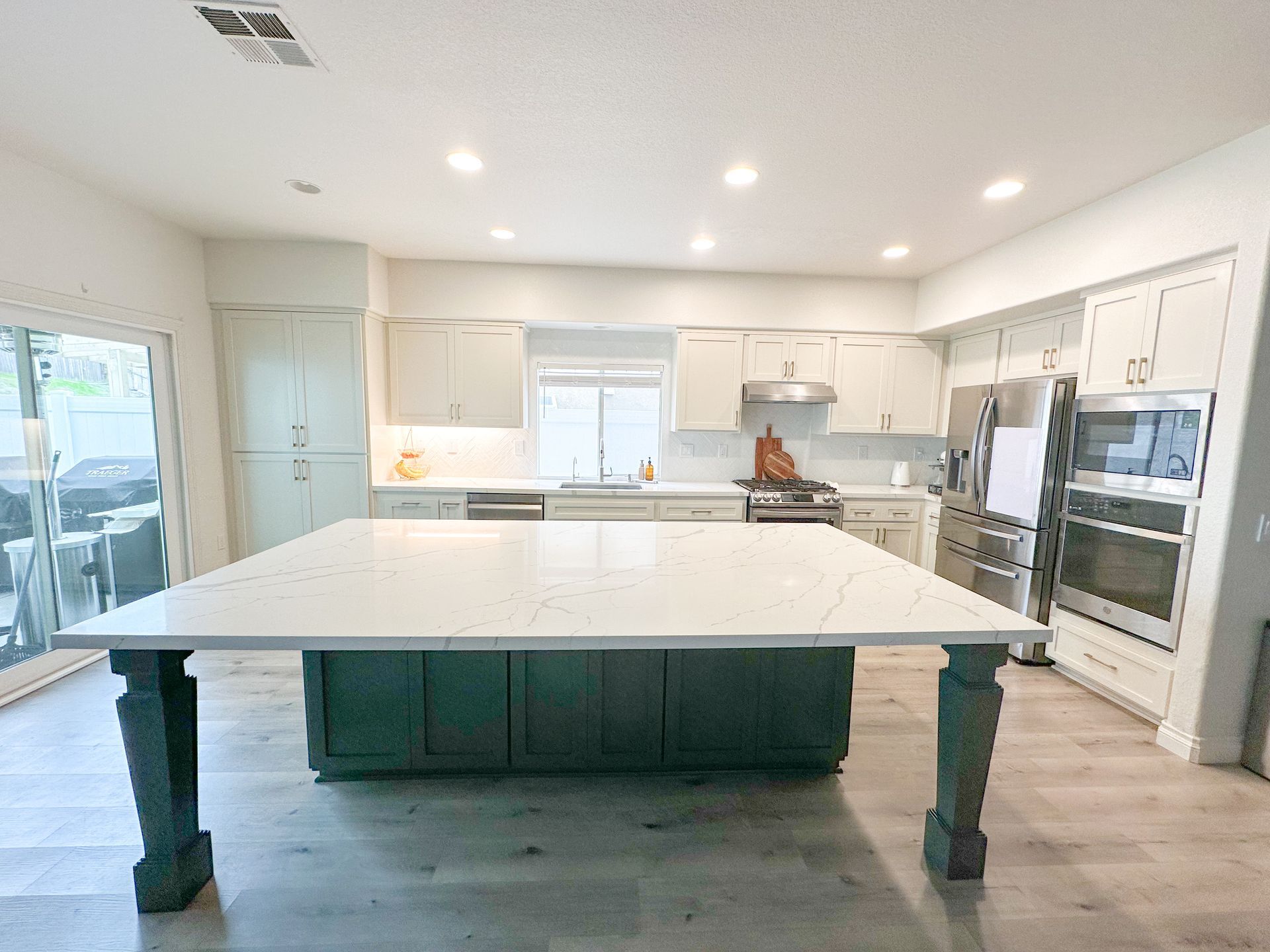 Bright modern kitchen with white cabinets and a large island table in the center