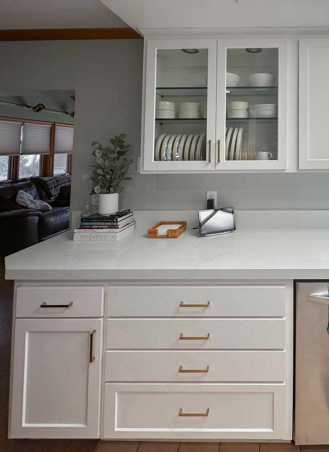 White kitchen counter with cabinets, open shelving, and a small tray of fruit and mail.