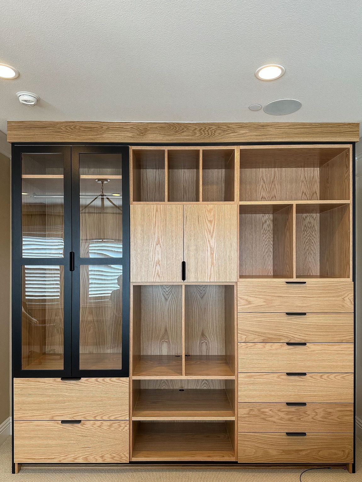 White wooden built-in bookshelf with central cabinet storage and drawers, positioned against a plain wall.