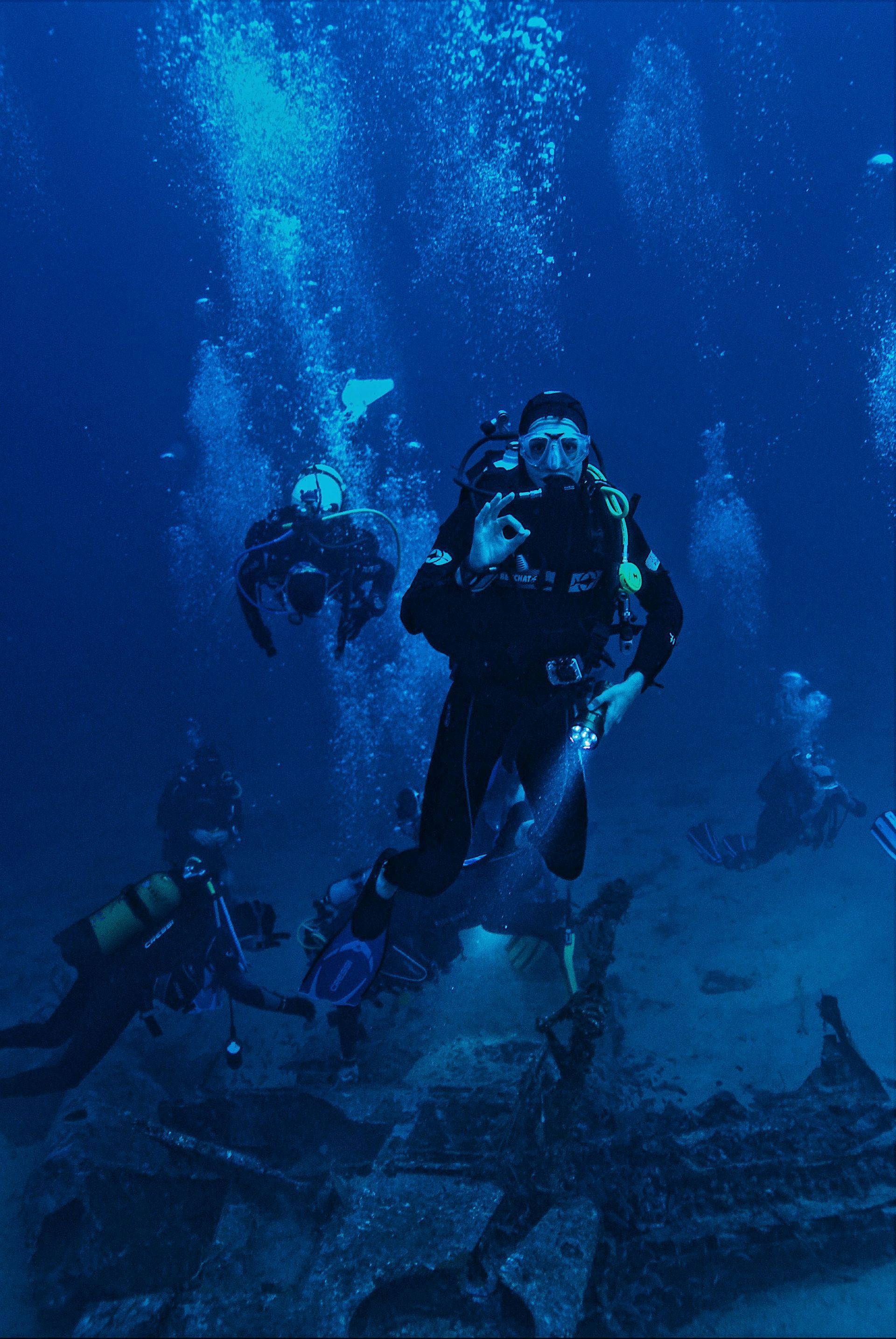 Divers exploring underwater, one giving an 