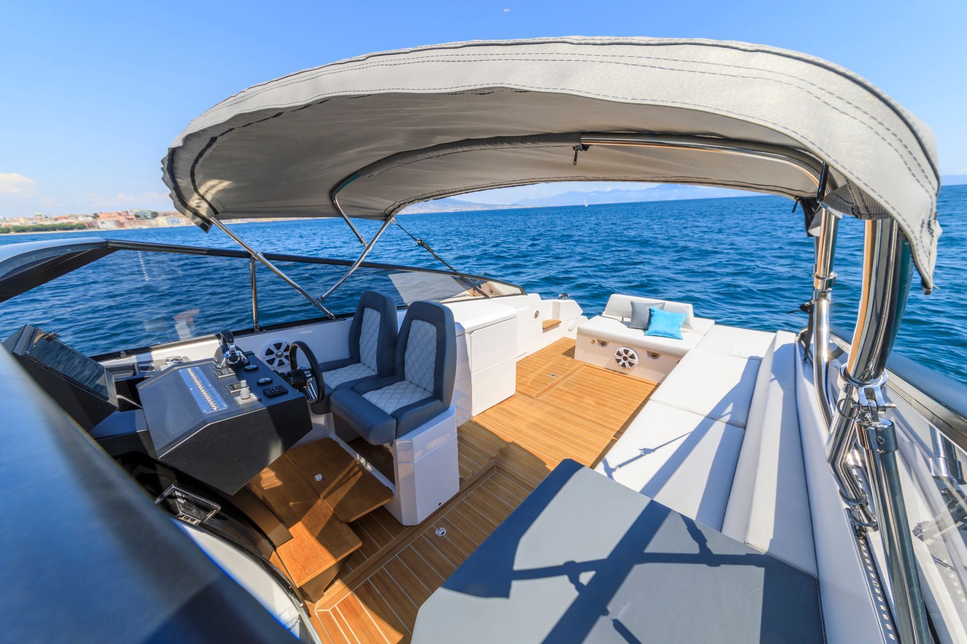 A motorboat on the ocean with a gray canopy, wooden deck, and seating for passengers.