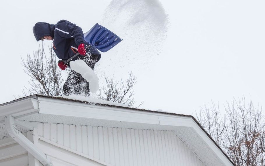 Person shoveling snow from a white roof on a winter day