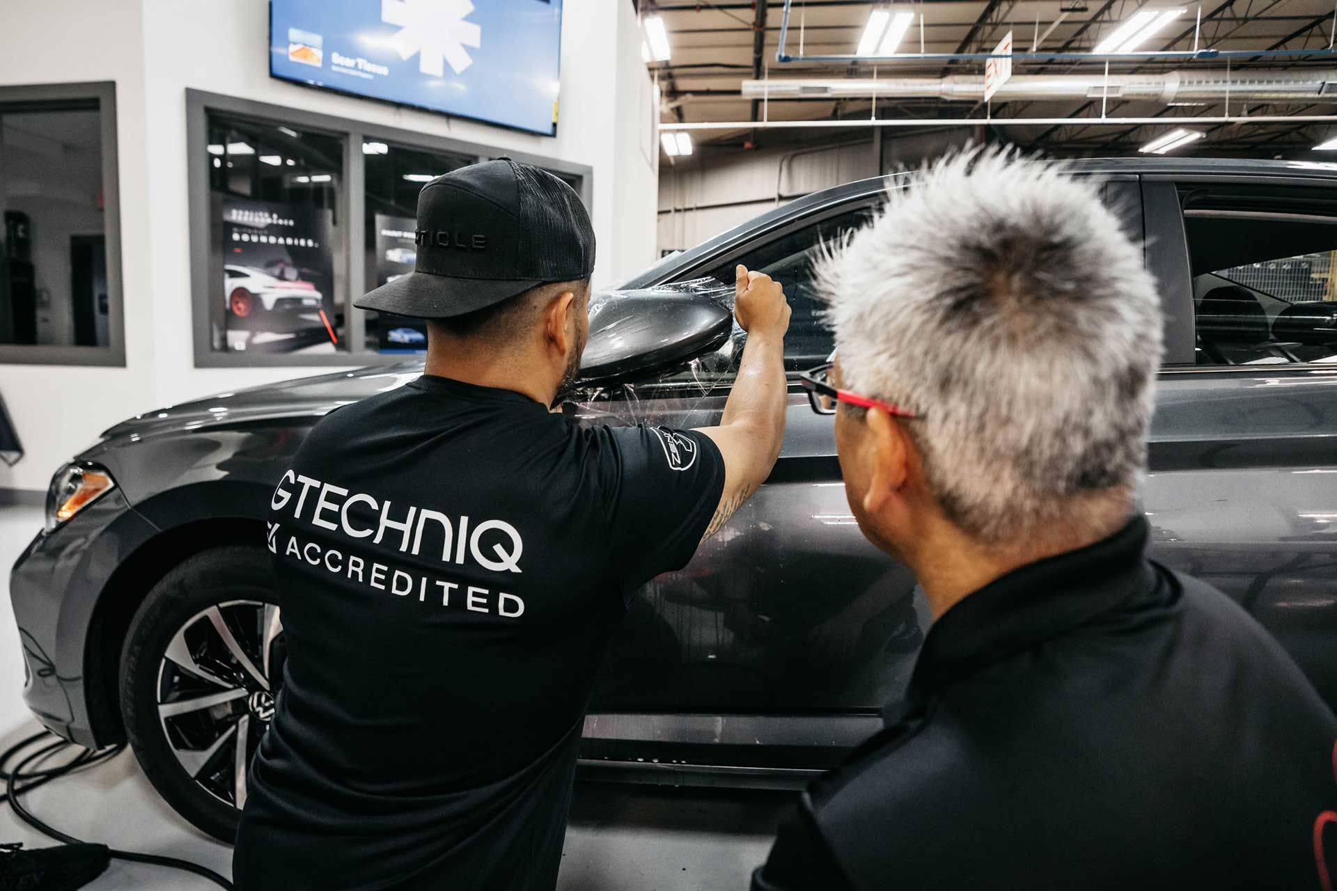 Two men are working on a car in a garage.