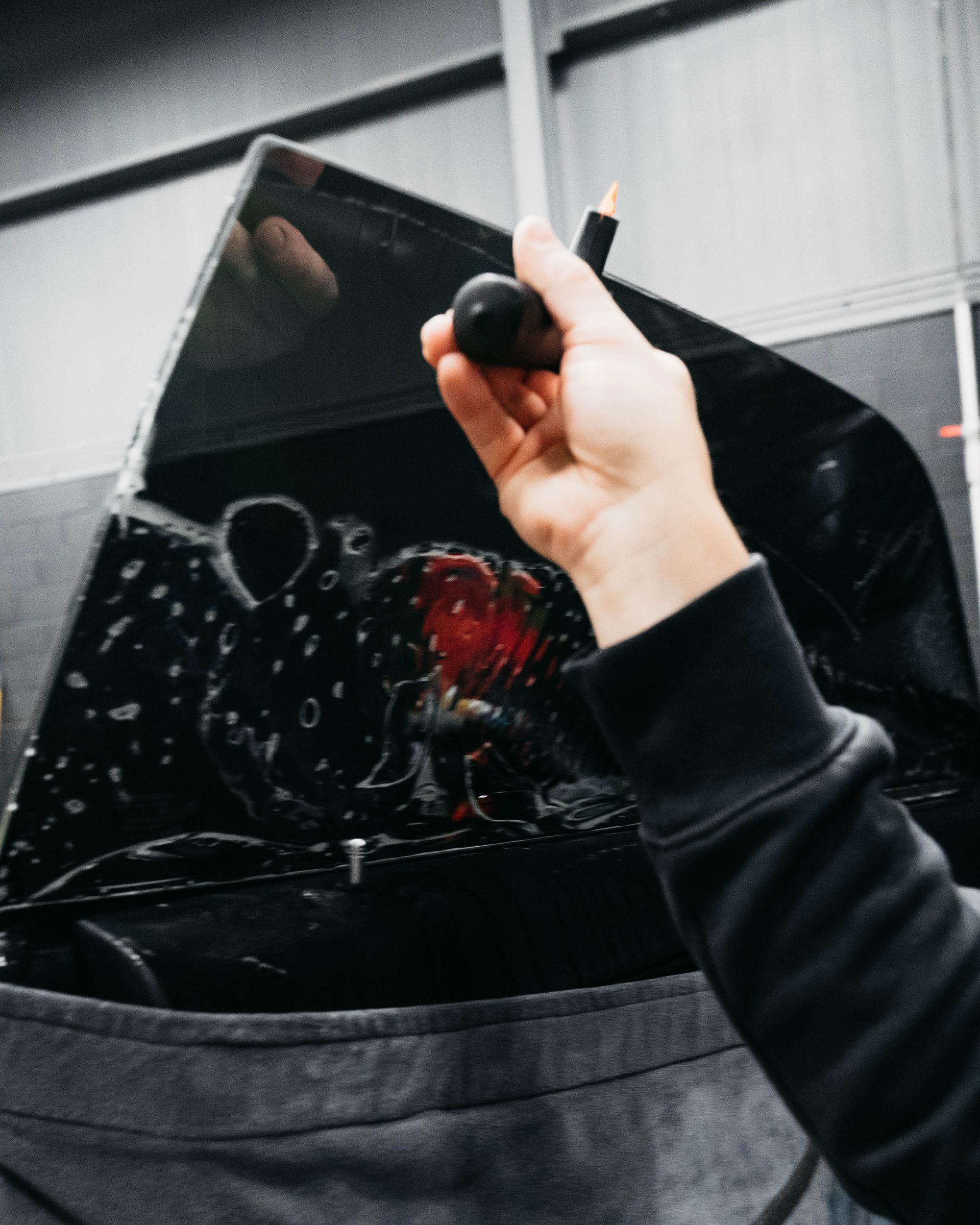 Hand holding a black umbrella with raindrops, inside a gray bag or pocket display