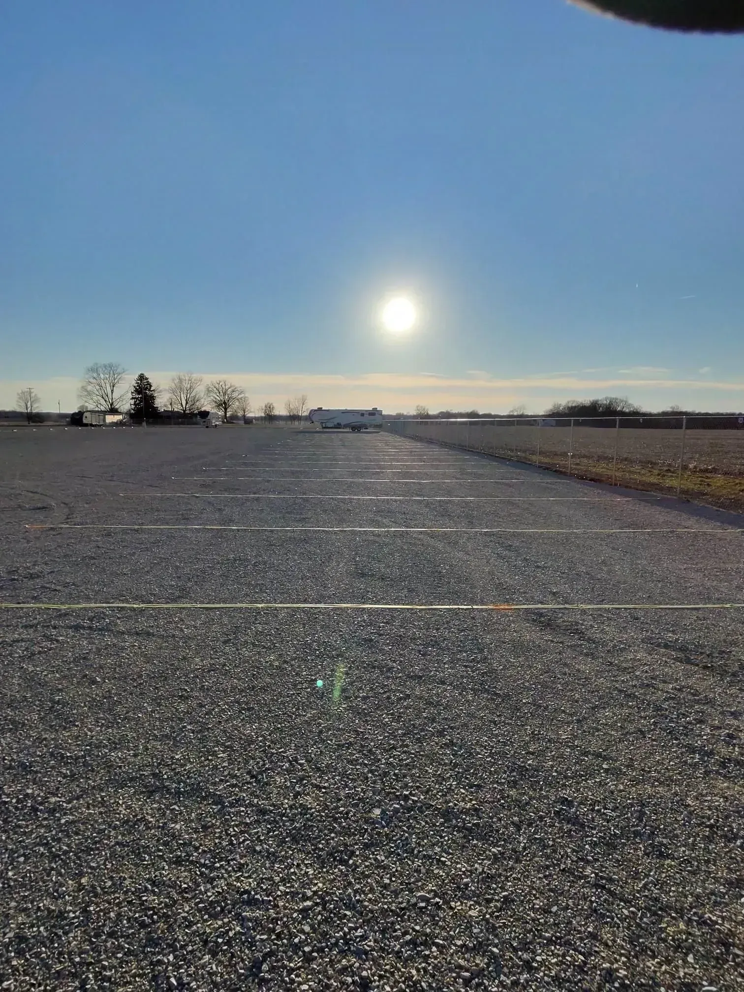 Long gravel lanes lined up for outdoor boat storage beneath a bright afternoon sun.