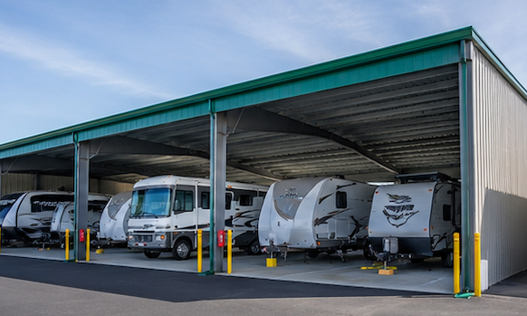 Covered RV storage lot with several parked motorhomes and trailers under a metal canopy