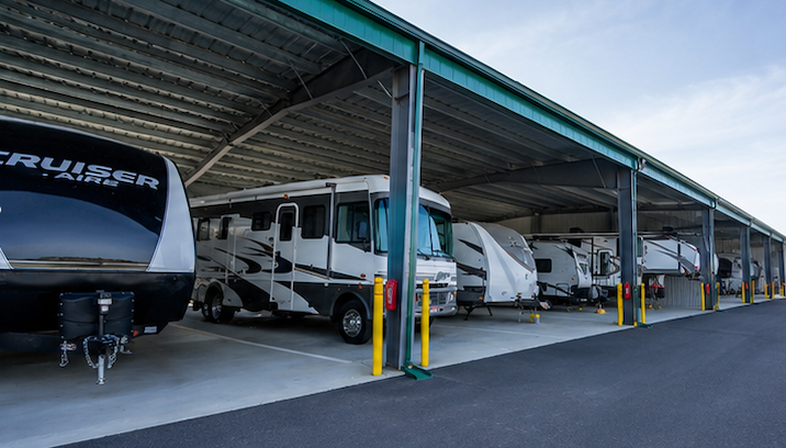 Covered RV storage lot with several parked motorhomes under a metal roof