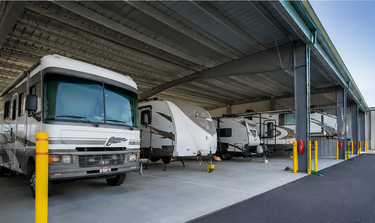 RVs parked under a covered lot with yellow posts and a gray concrete floor