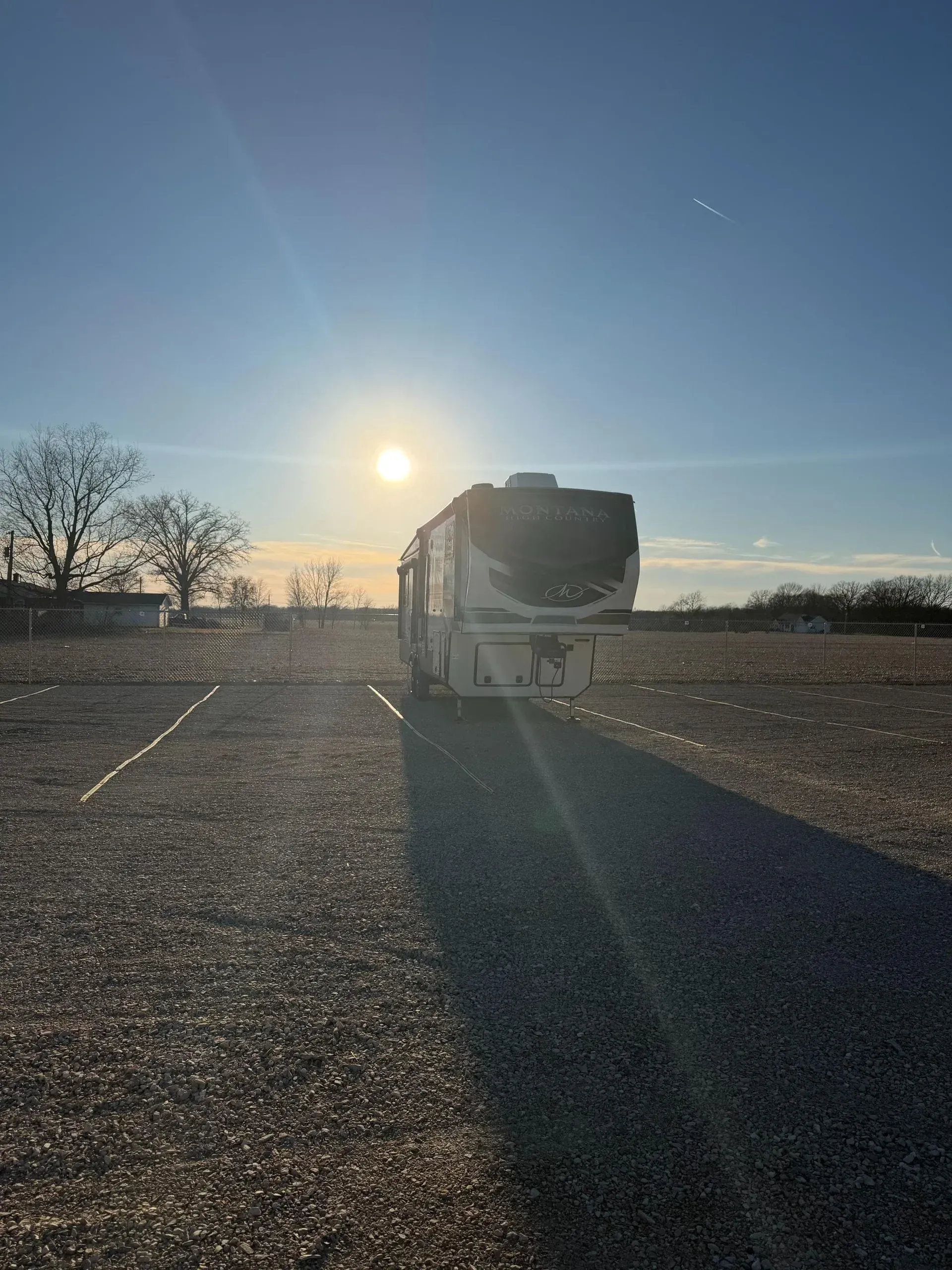 A luxury fifth wheel camper parked in a dedicated outdoor storage space at sunrise.