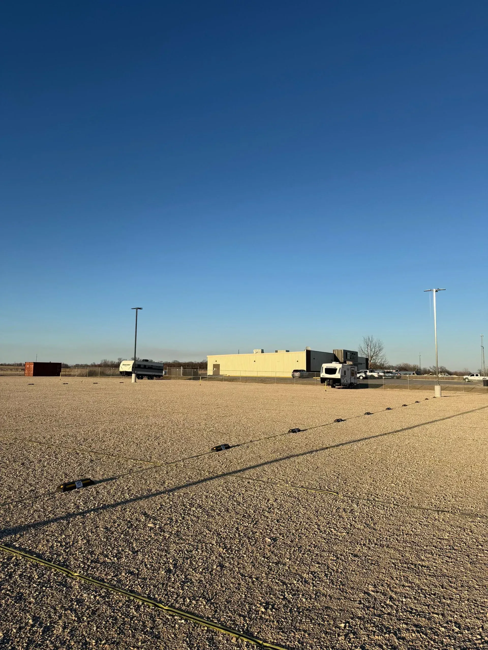Wide gravel driving aisles and numbered spaces inside a secure trailer storage yard.