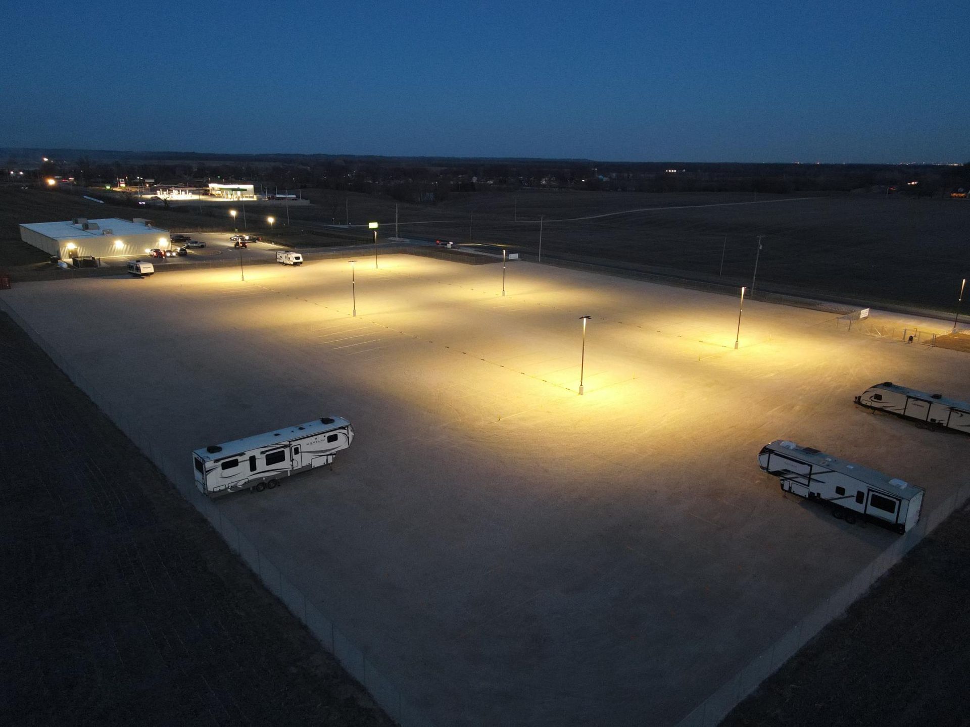 Overhead nighttime view of a lit RV parking lot with several RVs parked.
