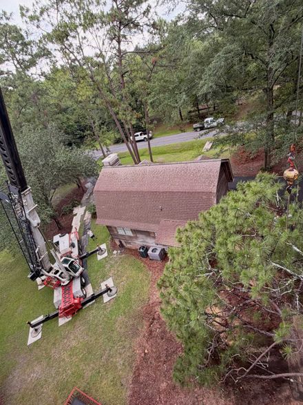Small backyard with a brown shed, trees, lawn, and a red-and-black mower or tractor near the left side.