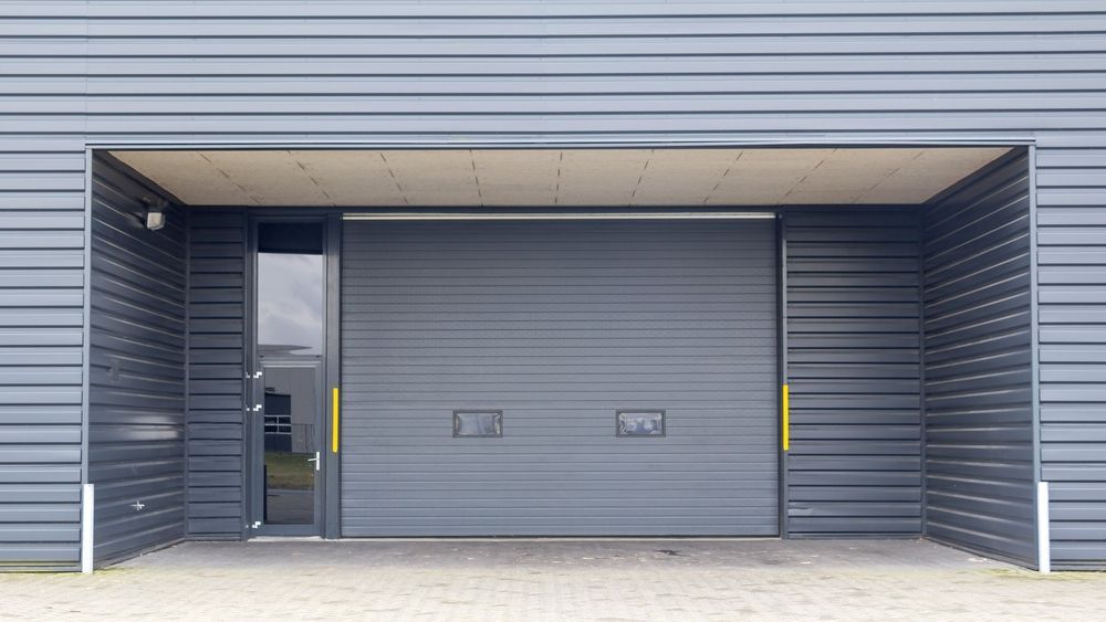 Gray Garage Door and Entry, Building Exterior With Dark Siding and Concrete — MJD Roofing Sunshine Coast in Cooroy, QLD